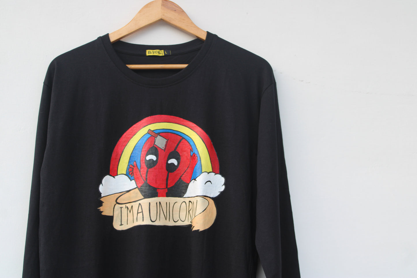 Close-up of a unique hand painted Deadpool T-shirt featuring a rainbow and a happy Deadpool with an "I'M A UNICORN" banner.