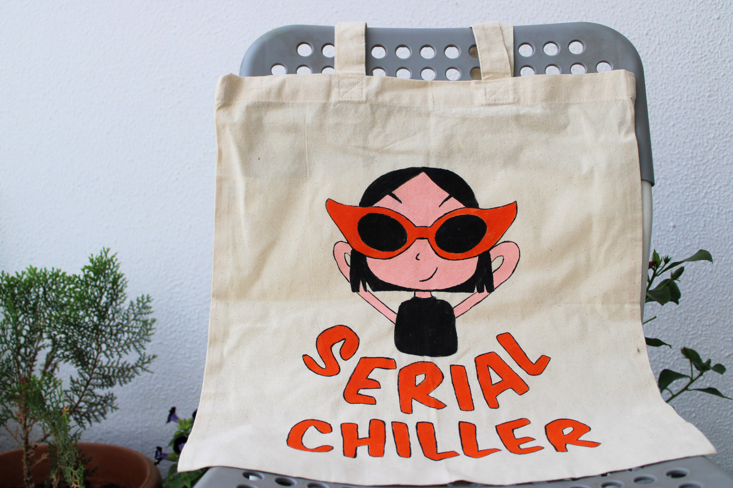 Full view of a unique hand-painted "Serial Chiller" tote bag on natural canvas, featuring a cool character with red sunglasses and the "Serial Chiller" text.