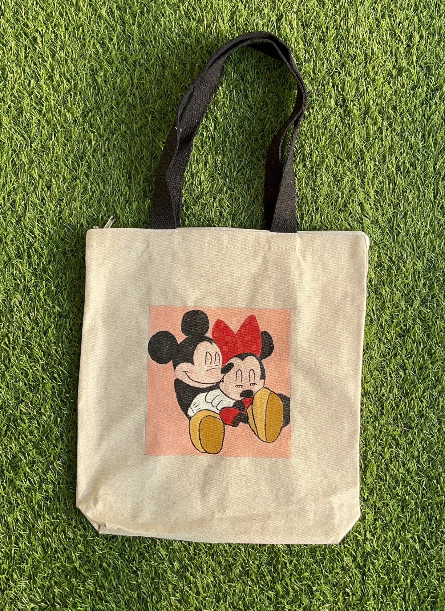Full view of a unique hand-painted Mickey and Minnie Mouse tote bag on natural canvas, showing the couple in a loving embrace.